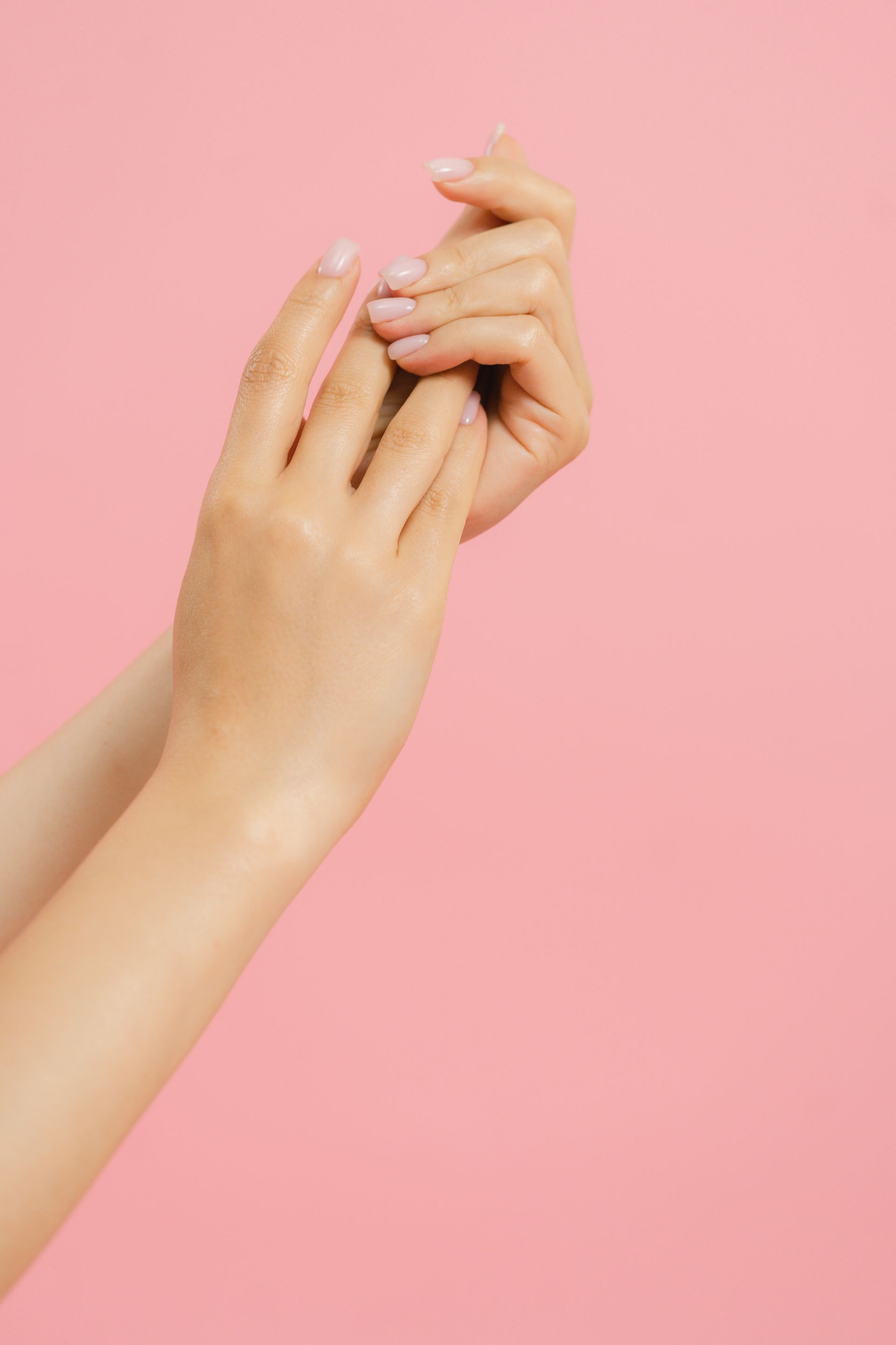 Soft pink manicure against a bright pink background