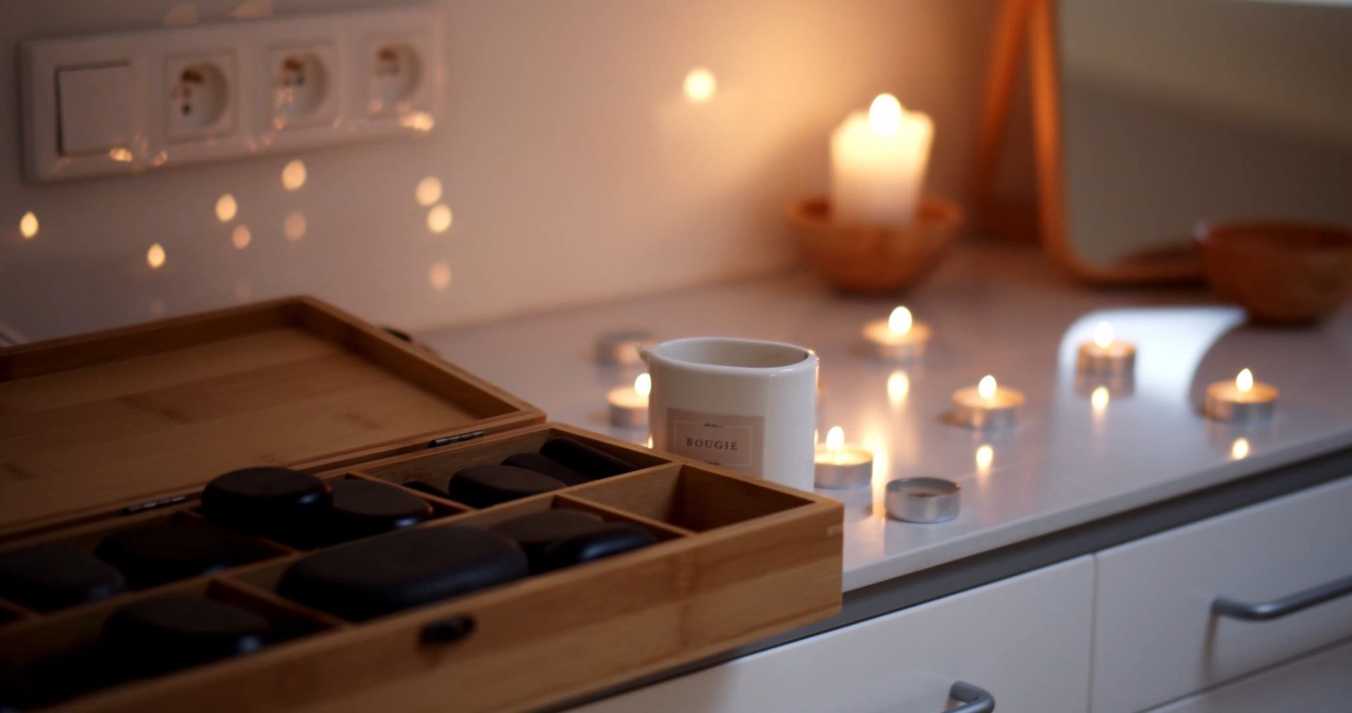 Warm candlelight beside smooth massage stones